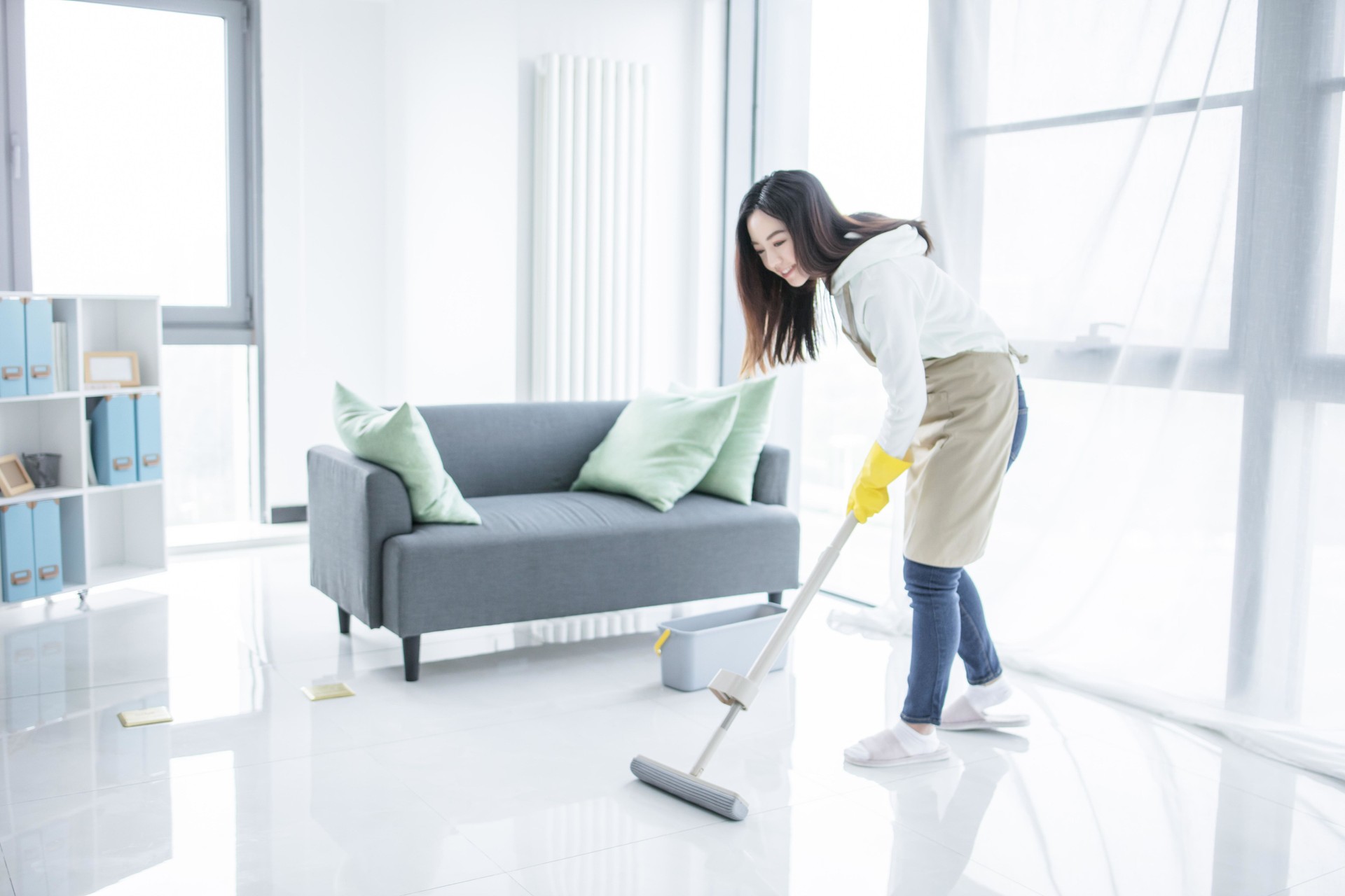 Asian woman mopping floor in living room